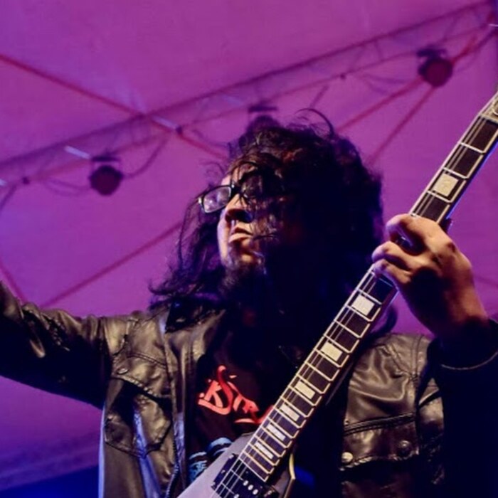 Samir Hafiz playing guitar on stage.